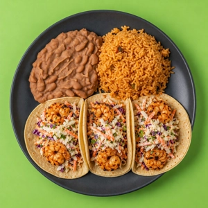 Shrimp taco plate with grilled shrimp, coleslaw, refried beans, and rice, served in Dallas.