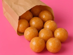 Donut holes with a glazed coating spilling from a brown paper bag on a pink surface in Dallas.