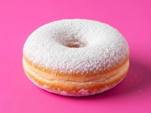 Sugar donut with powdered sugar on a pink background in Dallas.