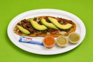 Huarache with beef, avocado, and lettuce on a white plate in Dallas.