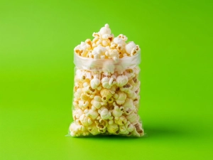 Small popcorn in a clear plastic bag with fluffy white kernels and a hint of butter on a green background in Dallas.