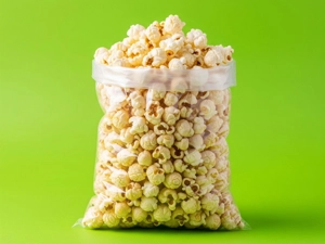 Medium popcorn in a clear plastic bag, showing fluffy popped corn against a green background in Dallas.