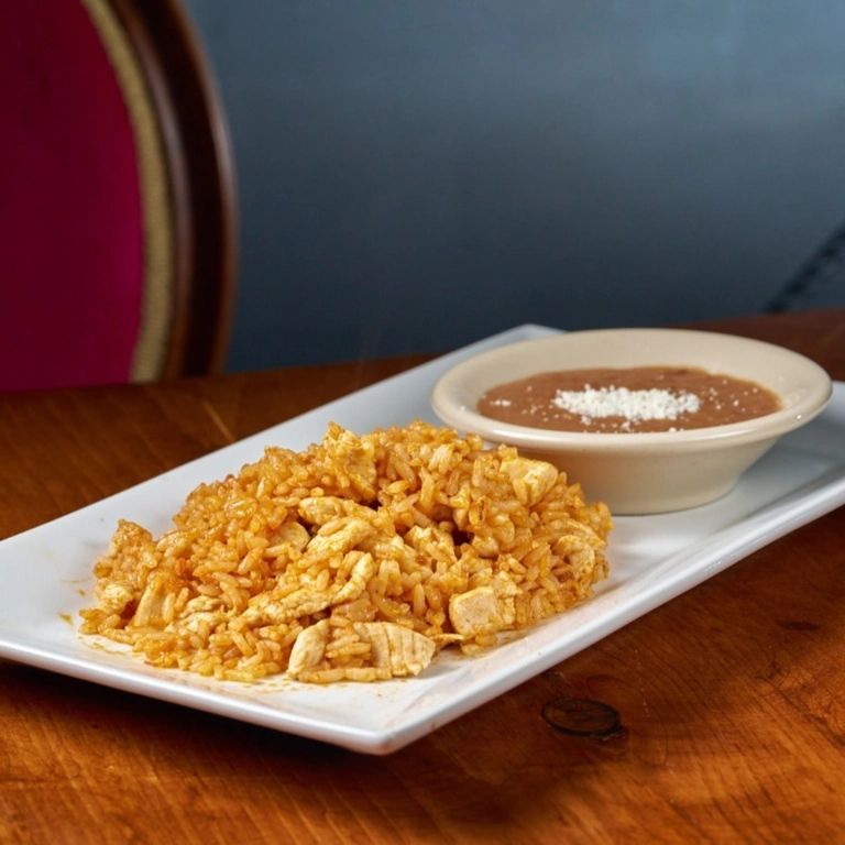 Kid Arroz con Pollo with visible chicken pieces and seasoned rice, served with a side of refried beans in Wantagh.