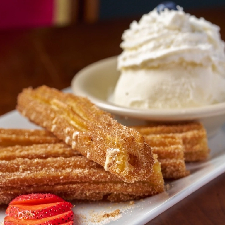 Churros with a caramel filling, served with banana ice cream and a slice of strawberry in Wantagh.