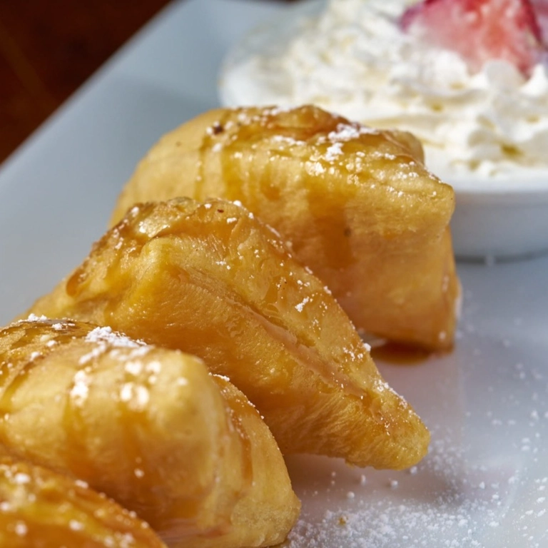 Sopapilla topped with honey and powdered sugar, served with whipped cream, in Wantagh.