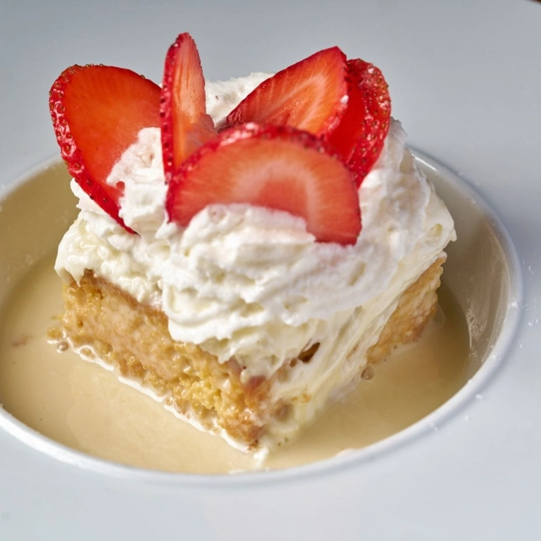 Tres Leches cake with whipped cream and sliced strawberries in Wantagh.