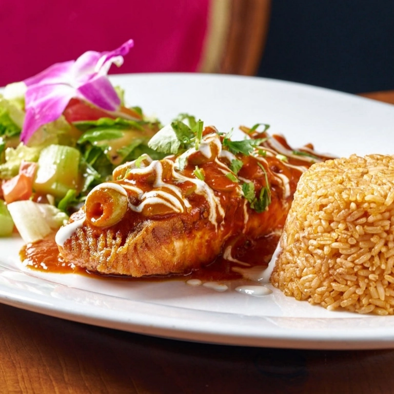 Mixiote de Salmon with sauce and rice, garnished with olives and cilantro, served with a side salad in Wantagh.