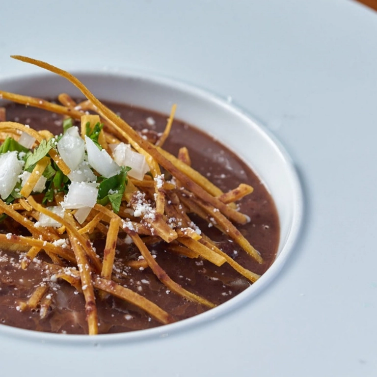 Sopa Negra with tortilla strips, onions, and cilantro in Wantagh.