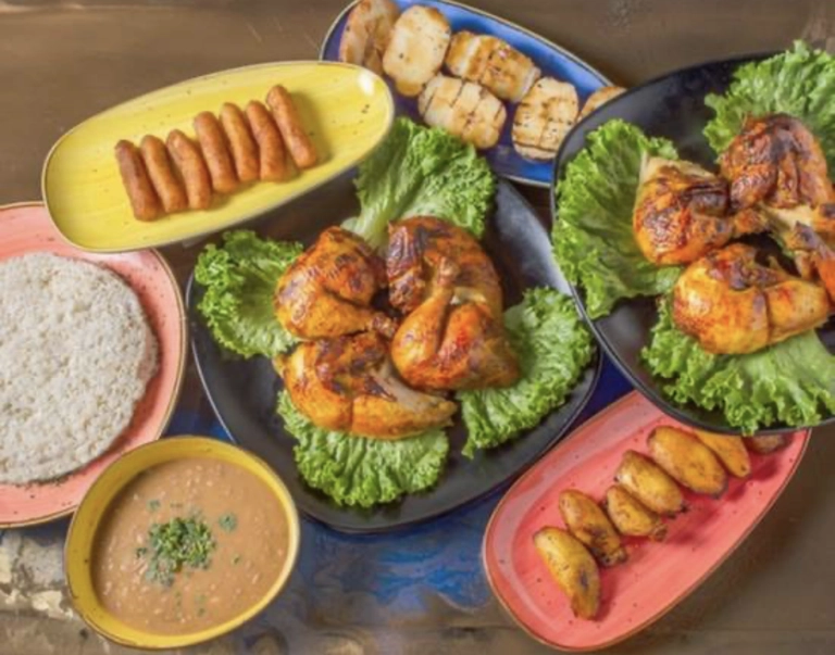 Combo familiar con dos pollos asados sobre lechuga, plátanos fritos y frijoles en un plato. Ciudad desconocida.