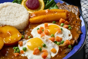 Bistec a caballo con huevos fritos y arroz blanco, acompañado de frijoles y ensalada en salsa criolla.