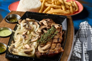 Baby churrasco con cebolla y champiñones, acompañado de arroz blanco y papas fritas. Cocina desconocida en ciudad