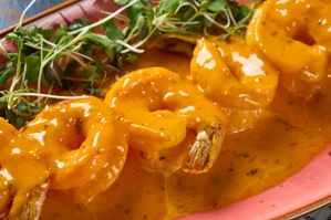 Langostinos al ajillo con salsa de ajo y brotes verdes visibles. Cocina desconocida en ciudad desconocida.