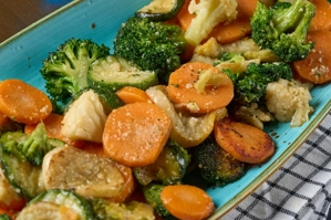 Vegetales mixtos con brócoli, zanahorias y calabacín en un plato azul. Ciudad desconocida.