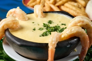 Crema de camarones con camarones visibles y cilantro. Papas fritas al fondo. Cocina desconocida en ciudad desconocida.