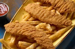 Dedos de pollo con papas fritas en un plato amarillo, acompañados de salsa roja. Cocina desconocida en ciudad no