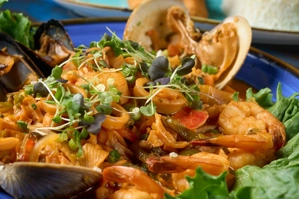 Salteado de mariscos con camarones y almejas visibles, acompañado de lechuga. Cocina desconocida en ciudad desconocida.