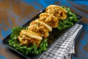 Arepitas con pollo desmenuzado y salsa hogao sobre una cama de lechuga. Cocina desconocida en una ciudad desconocida.