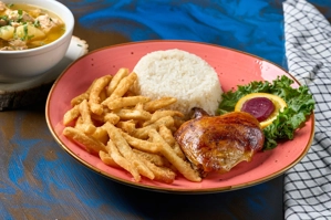 Bandeja de pollo al carbón con papas fritas y arroz blanco. Incluye ensalada con rodaja de naranja y remolacha. Ciudad