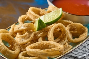 Calamares fritos con rodajas de lima y salsa marinara al lado. Cocina desconocida en ciudad desconocida.