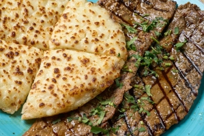 Carne asada con arepa, mostrando carne a la parrilla y arepa de maíz con queso. Cocina desconocida en ciudad desconocida.