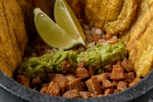 Tostirrón con plátanos verdes fritos, guacamole y chicharrón. Cocina desconocida en ciudad desconocida.