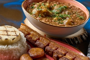 Frijoles con garra con chicharrón y arroz en un plato. Arepa y plátanos maduros fritos al lado. Cocina colombiana en una