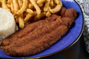 Filete apanado con arroz blanco y papas fritas en un plato azul, cocina desconocida en ciudad desconocida.