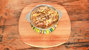 Sencillos con carne, papas fritas y maíz en un plato sobre una mesa de madera. Cocina desconocida en ciudad desconocida.