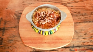 Sencillos con tocineta, papas fritas y salsa en un plato de metal sobre una tabla de madera. Ciudad desconocida.