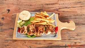 Chuzo de pollo con arepa, papas fritas y rodajas de limón. Cocina desconocida en ciudad desconocida.
