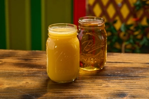 Jugo de naranja en un frasco de vidrio sobre una mesa de madera. Al fondo, otro frasco vacío. Ciudad desconocida.