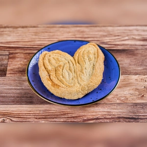 Orejas pastry on a blue plate, showing flaky layers and sugar coating. Cuisine type and city unknown.