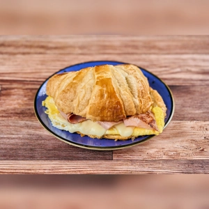 Croissant with egg, ham, and melted cheese on a plate. Unknown cuisine in an unknown city.