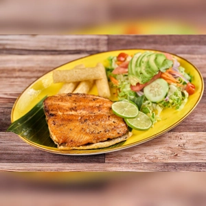 Grilled salmon with lime slices, yuca fries, and a fresh salad with avocado and cucumber. Cuisine type and city unknown.