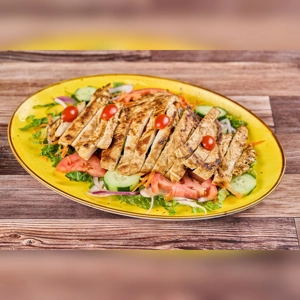 Ensalada de Pollo with grilled chicken, cherry tomatoes, and cucumbers on a yellow plate. Cuisine type and city unknown.
