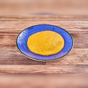 Arepa De Huevo, a Colombian dish, with a golden fried cornmeal exterior on a blue plate. City unknown.