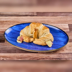 Croissant with visible ham and cheese on a blue plate. Cuisine type and city unknown.