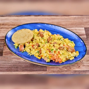 Huevos Rancheros with Arepa featuring scrambled eggs, sausage, and tomatoes on a blue plate. Cuisine type unknown.