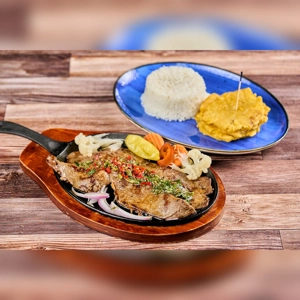 Carne Asada with grilled beef, onions, and rice on a wooden table. Cuisine type and city unknown.