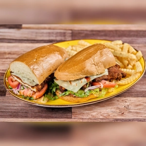 Chicken Milanese Sandwich with lettuce, tomato, and cheese on a yellow plate with crinkle-cut fries. Cuisine type unknown.