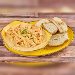 Fettuccine Alfredo with shrimp and parsley, served with slices of bread. Cuisine type and city unknown.