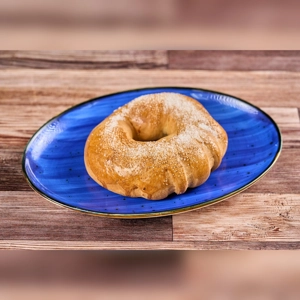 Roscon de Guayaba Grande with a golden crust and sugar topping on a blue plate. Unknown city.