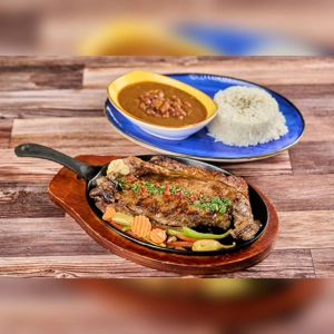 Churrasco steak with grilled vegetables and herbs, served with rice and beans. Cuisine type and city unknown.