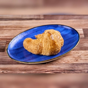 Plain croissant on a blue plate, showcasing its flaky layers. Cuisine type and city unknown.