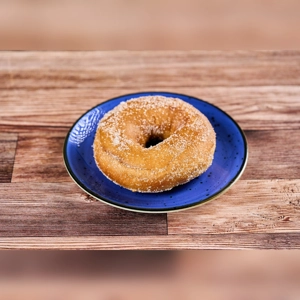 Donut on a blue plate, sprinkled with sugar, on a wooden table. Cuisine type and city unknown.