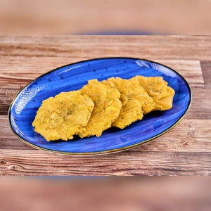 Extra tostones on a blue plate, showing crispy fried plantains, likely in a Latin American style, in an unknown city.