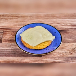 Arepa de Choclo with melted cheese on a blue plate, showcasing Colombian cuisine in an unknown city.