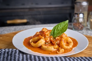 Calamari Marinara with rings of calamari, tomato sauce, and fresh basil on a white plate in New York.