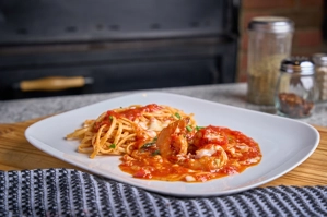 Shrimp Fra Diavolo with spaghetti and spicy red tomato sauce on a white plate. Italian cuisine in New York.