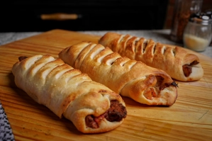 Meat stromboli with golden-brown crust and visible meat filling on a wooden board.